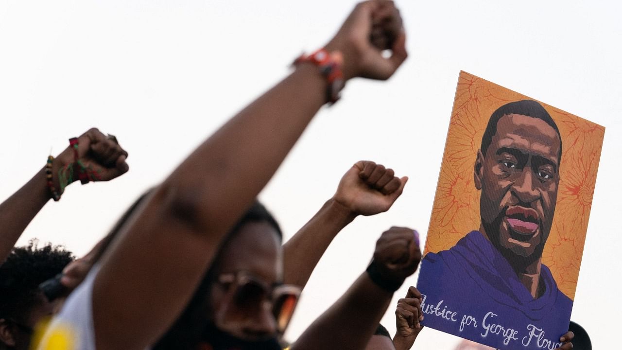 People raise their fists and hold a portrait of George Floyd during a rally following the guilty verdict the trial of Derek Chauvin on April 20, 2021, in Atlanta, Georgia. Credit: AFP Photo