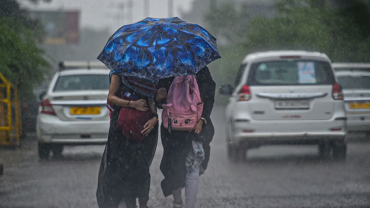 Women walk under an umbrella during a heavy shower, in New Delhi. Credit: PTI Photo