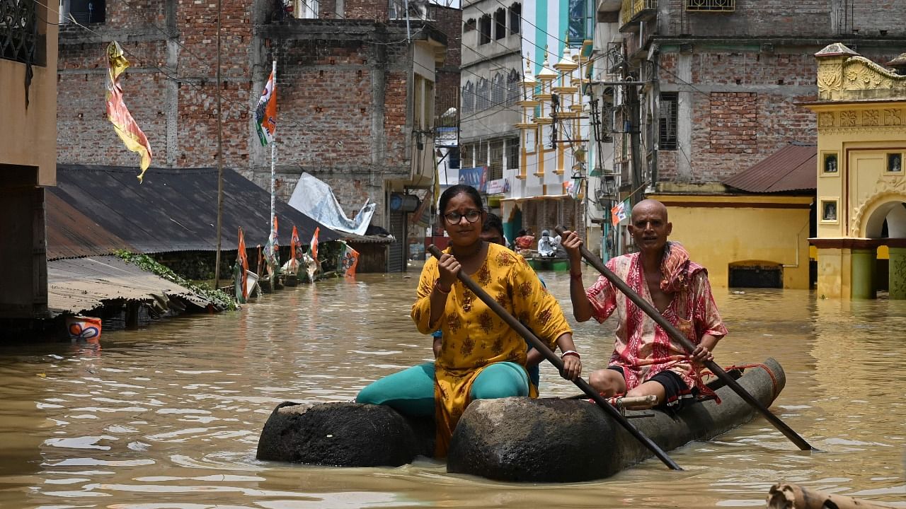 Residents ride a boat over a road submerged by floodwaters following heavy monsoon rains in Ghatal, Paschim Medinipur district. Credit: AFP Photo