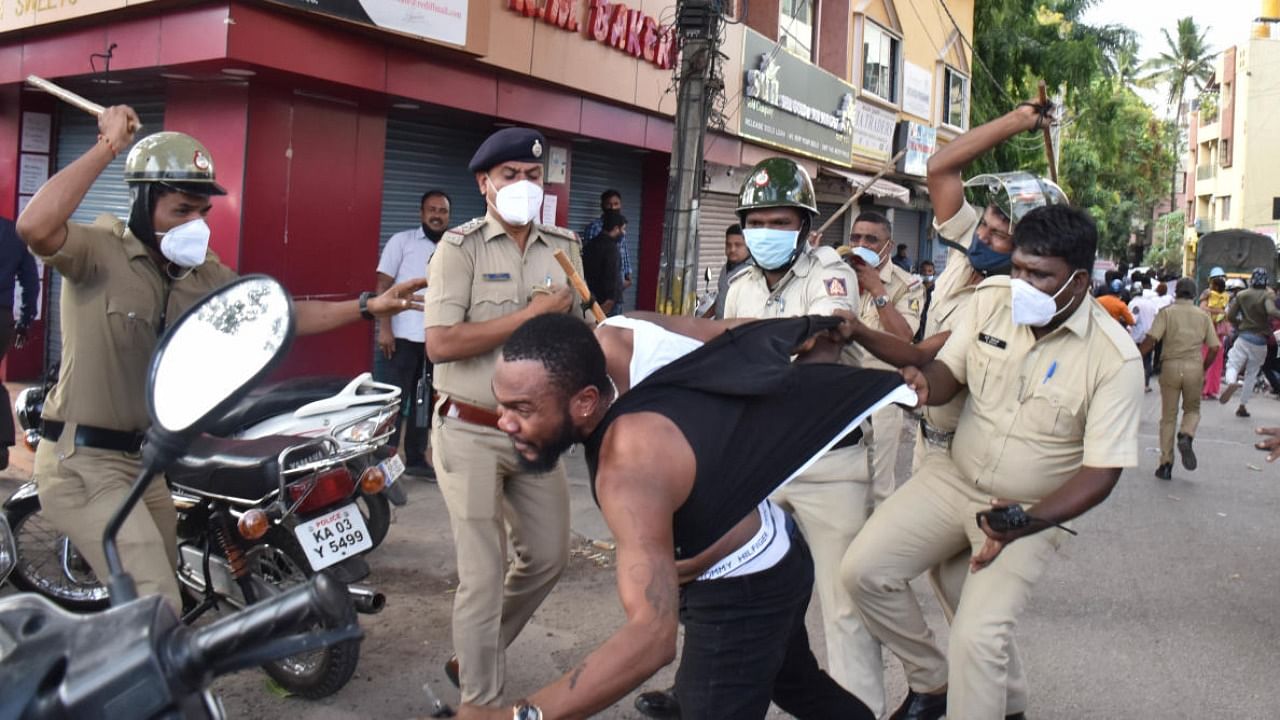 Cops lathi-charge an African during the scuffle that broke out after the flash protest outside the JC Nagar police station on Monday. Credit: DH Photo
