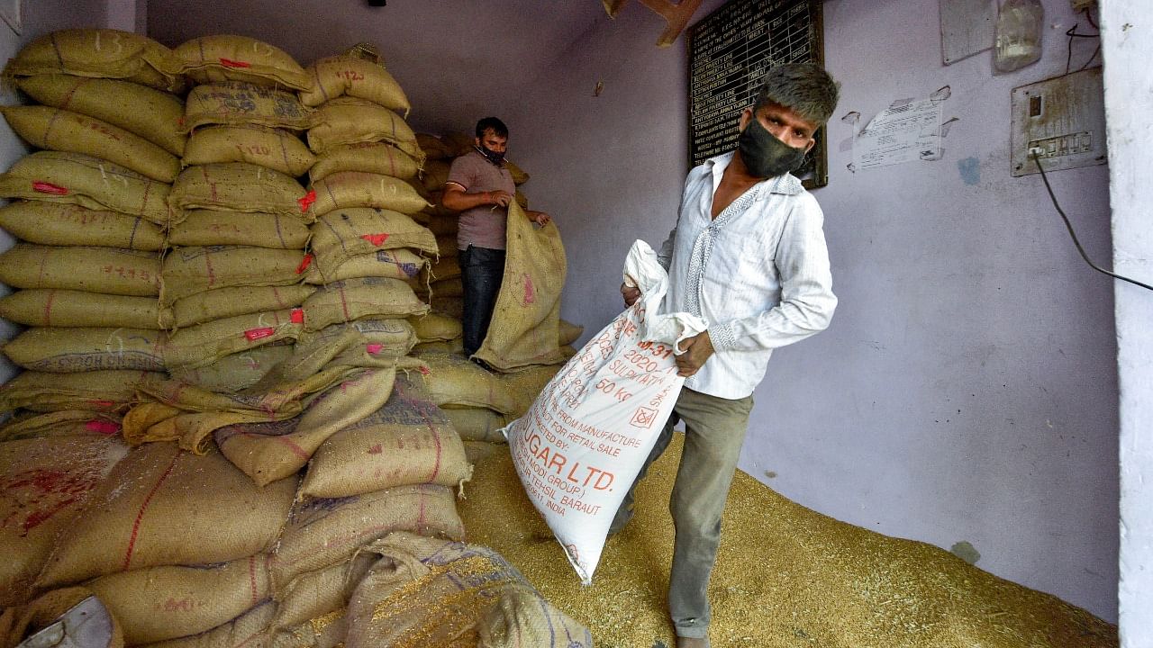 Labourers manage the sacks filled with free ration provided by the Central government at a shop in East Delhi. Credit: PTI File Photo