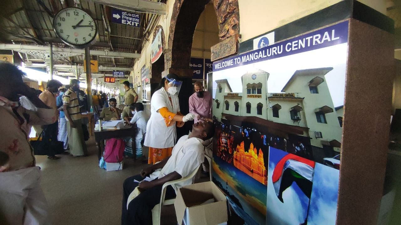 Swab is collected from passengers arriving from Kerala and Maharashtra at Mangaluru Central Railway Station on MOnday. Credit: DH Photo/Irshad Mahammad