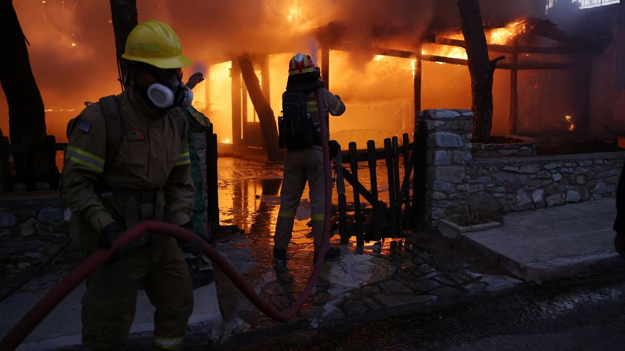 Firefighters try to extinguish a wildfire at Varympompi suburb north of Athens, Greece, August 3, 2021. Credit: Reuters Photo