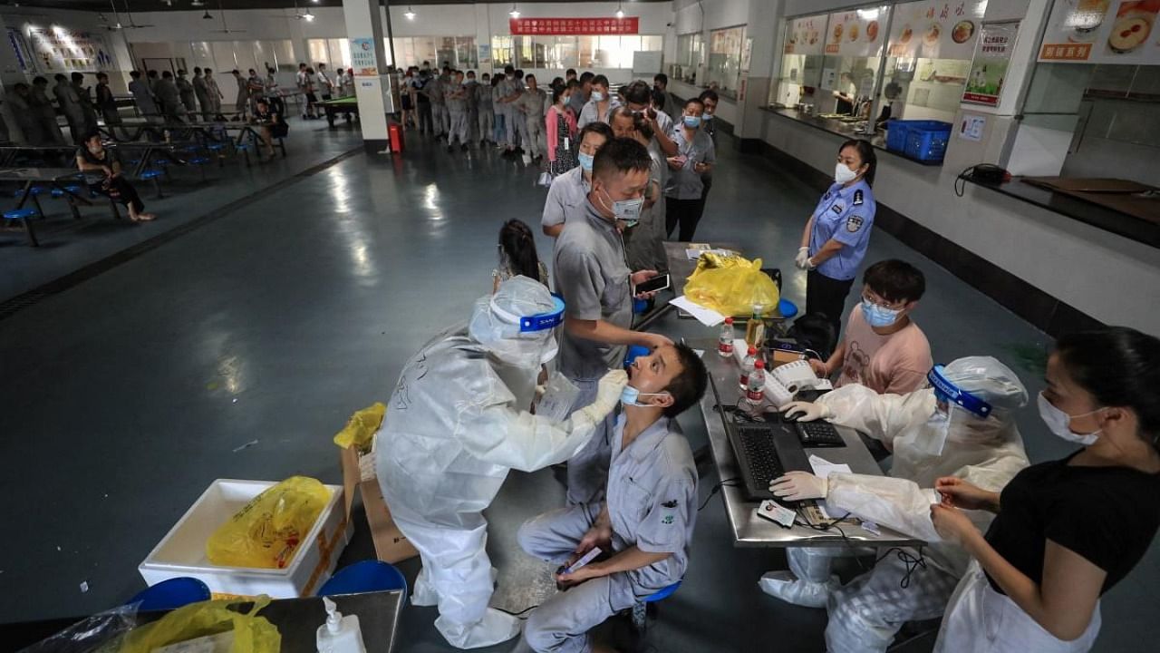A worker receives a nucleic acid test for the Covid-19 coronavirus at the dining hall of a car parts factory in Wuhan, in China's central Hubei province. Credit: AFP Photo