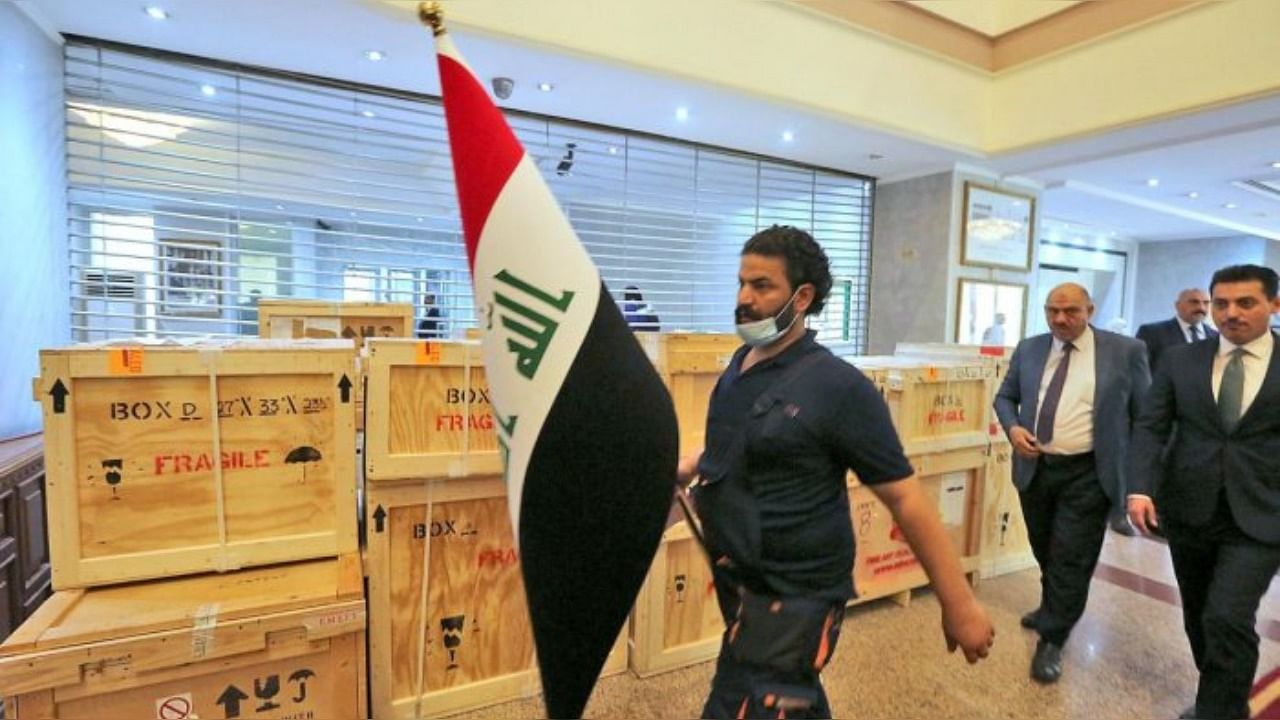 Staff members at Iraq's Ministry of Foreign Affairs work around crates of looted Iraqi antiquities returned by the United States, ahead of a handover ceremony at the ministry in the capital Baghdad, on August 3, 2021. Credit: AFP Photo