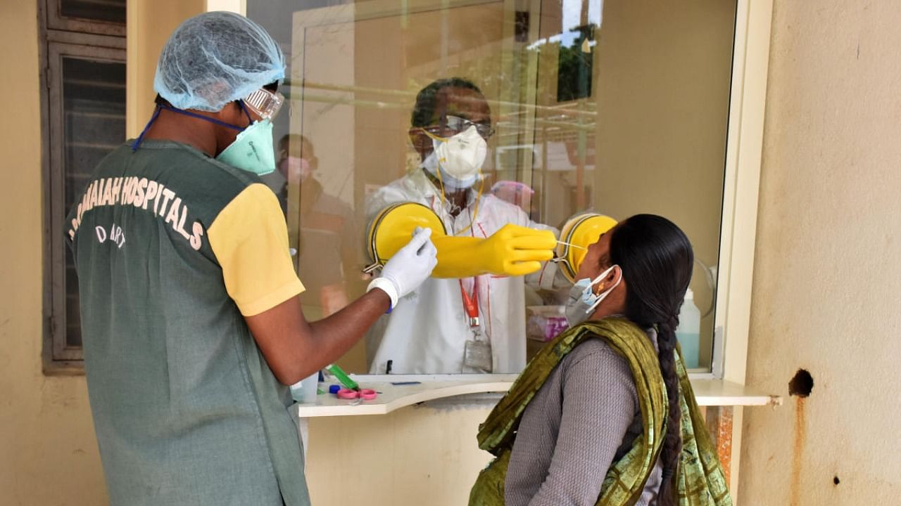 A health worker collects swab samples from a woman for Covid test at a private hospital in in Bengaluru on Tuesday. Credit: DH Photo/B K Janardhan