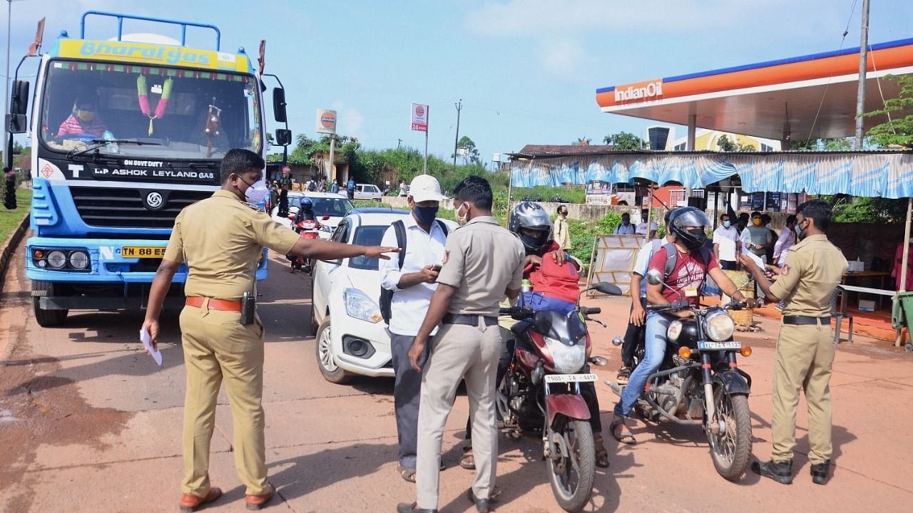 Police personnel check the Covid-19 test report of travellers at Talapady checkpost at Kerala-Karnataka border in Mangaluru, Monday, August 2, 2021. Credit: PTI Photo