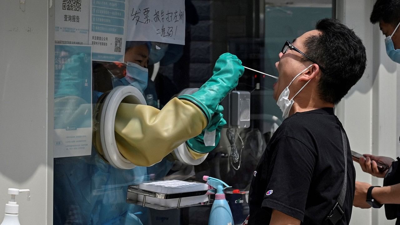 A health worker takes a swab sample from a man to be tested for Covid-19 coronavirus at a nucleic acid sample collection station in Beijing. Credit: AFP Photo