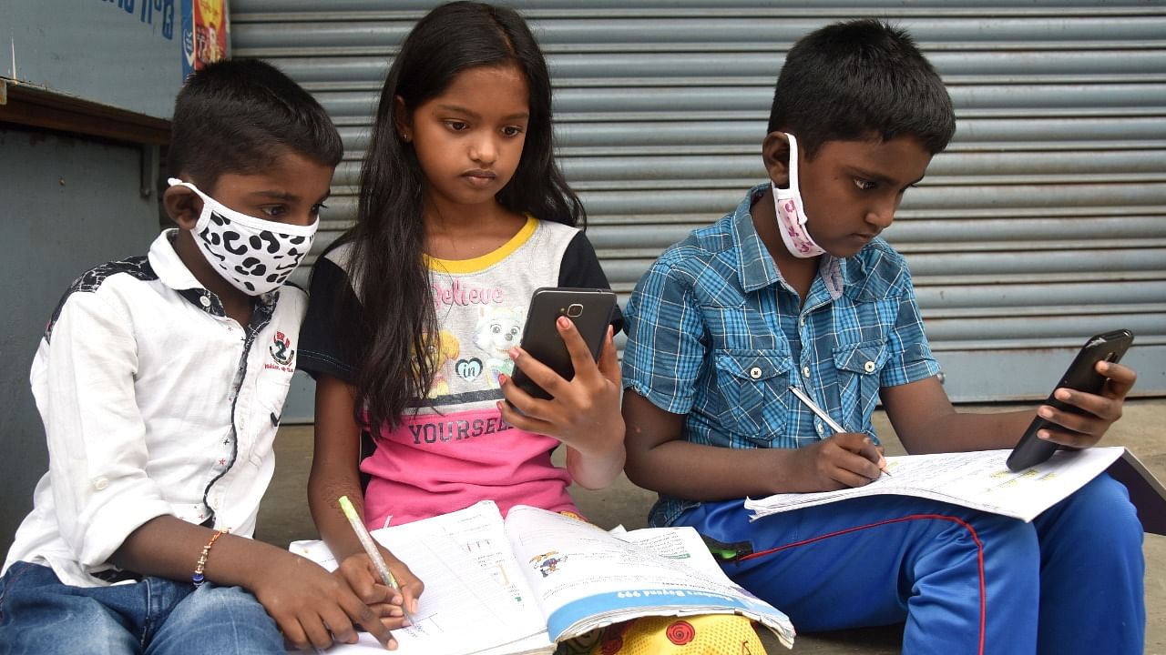 Children learning lesson from online classes through mobile at Bapuji Nagara in Bengaluru. Credit: DH File Photo