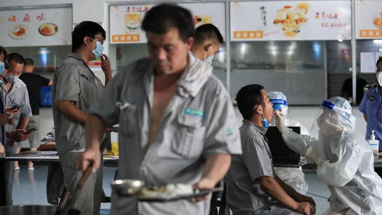 A worker receives a nucleic acid test for the Covid-19 coronavirus at the dining hall of a car parts factory in Wuhan, in China's central Hubei province on August 4, 2021. Credit: AFP Photo
