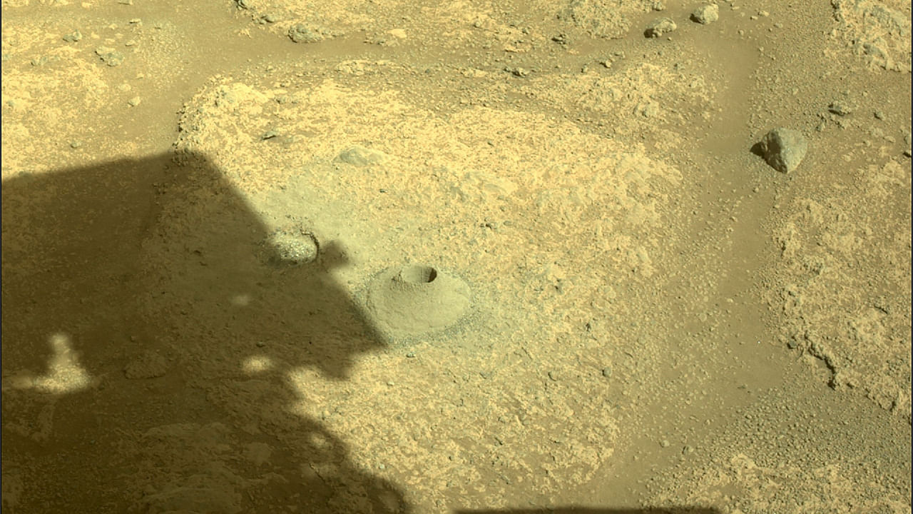 Shadow of the Perseverance Mars rover is cast next to its first hole drilled in a rock. Credit: AFP Photo