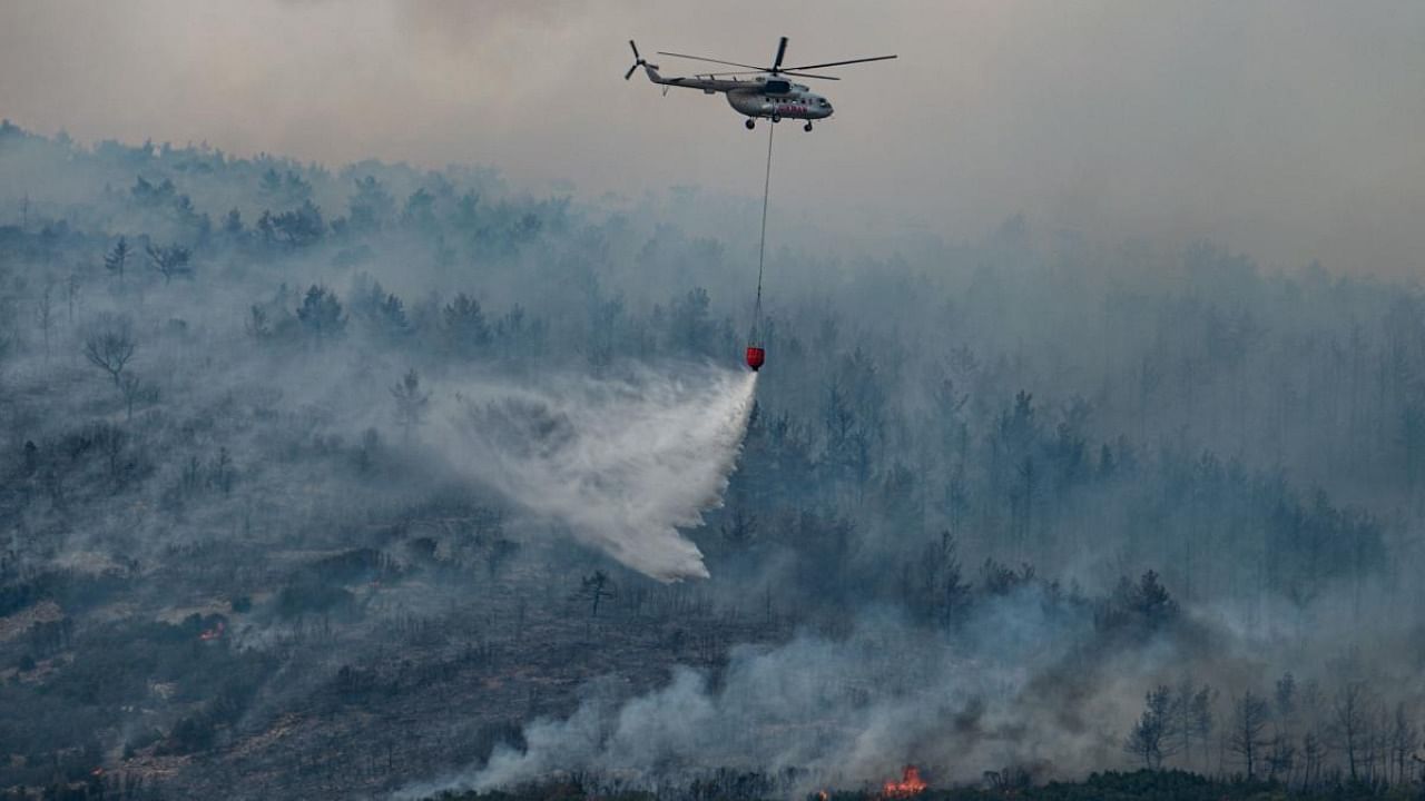 A helicopter drops water on a wildfire on an area near the village of Ikizce, in the Mugla province, on August 6, 2021. - In Turkey, at least eight people have been killed and dozens more hospitalised as the country struggles against its deadliest wildfires in decades. Credit: AFP Photo