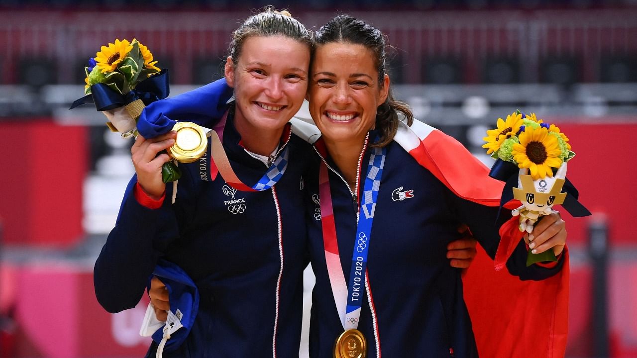 France's goalkeeper Amandine Leynaud (L) and France's goalkeeper Cleopatre Darleux celebrate with their gold medals on the podium after the women's handball event of the Tokyo 2020 Olympic Games at the Yoyogi National Stadium in Tokyo. Credit: AFP photo