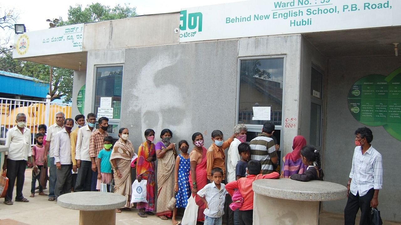 People stand in a queue in front of an Indira Canteen in Old Hubballi. Credit: DH Photo