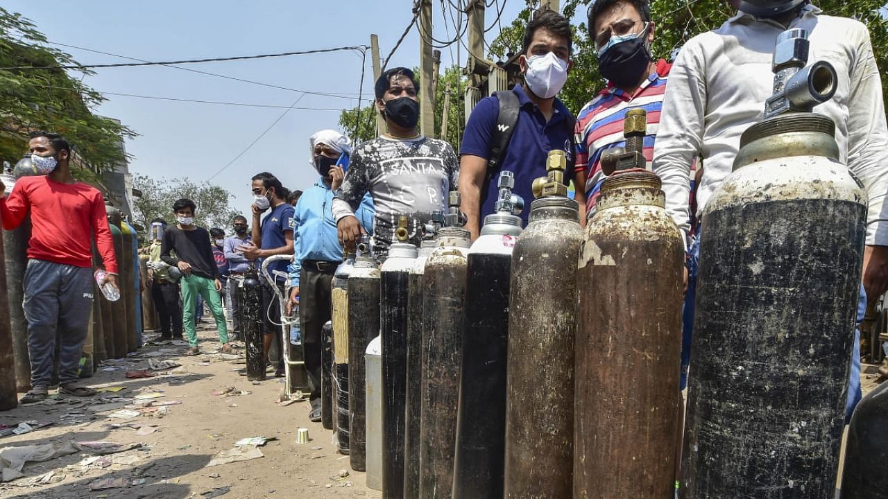 Family members of Covid-19 patients wait outside an oxygen-filling centre to refill their empty cylinders in New Delhi. Credit: PTI Photo