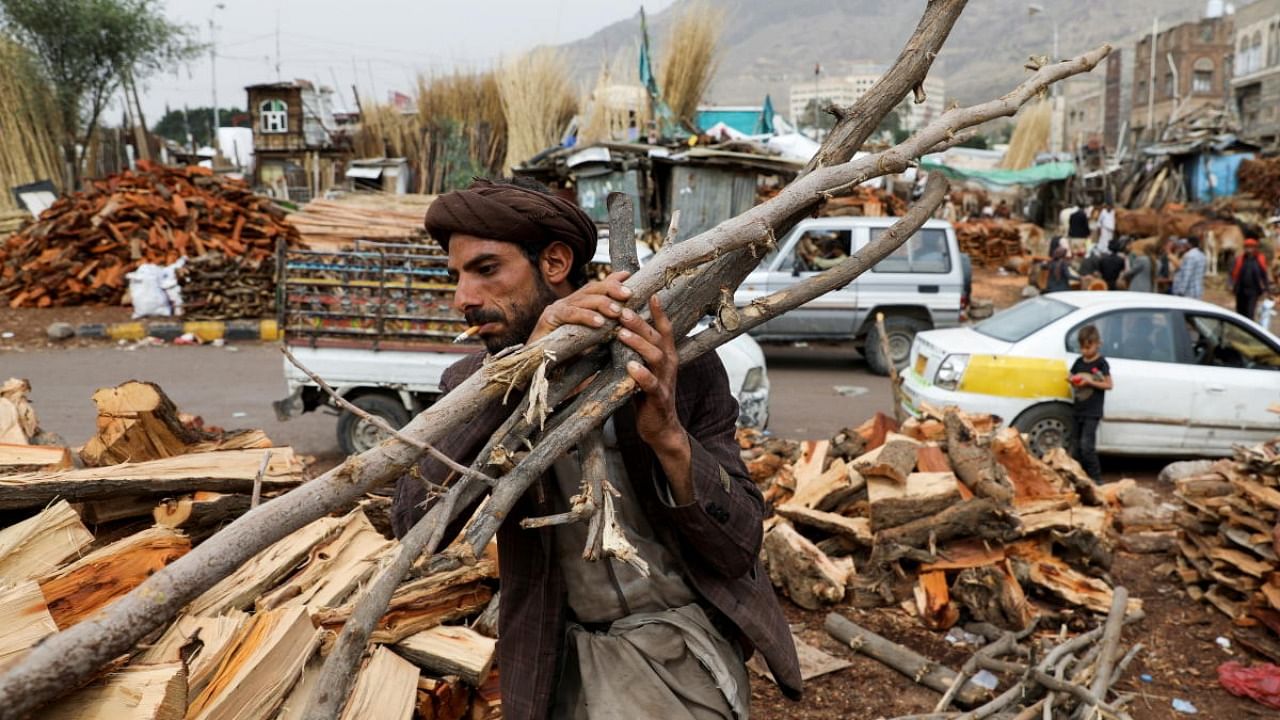 A vendor carries wood at a firewood market in Sanaa, Yemen. Credit: Reuters Photo