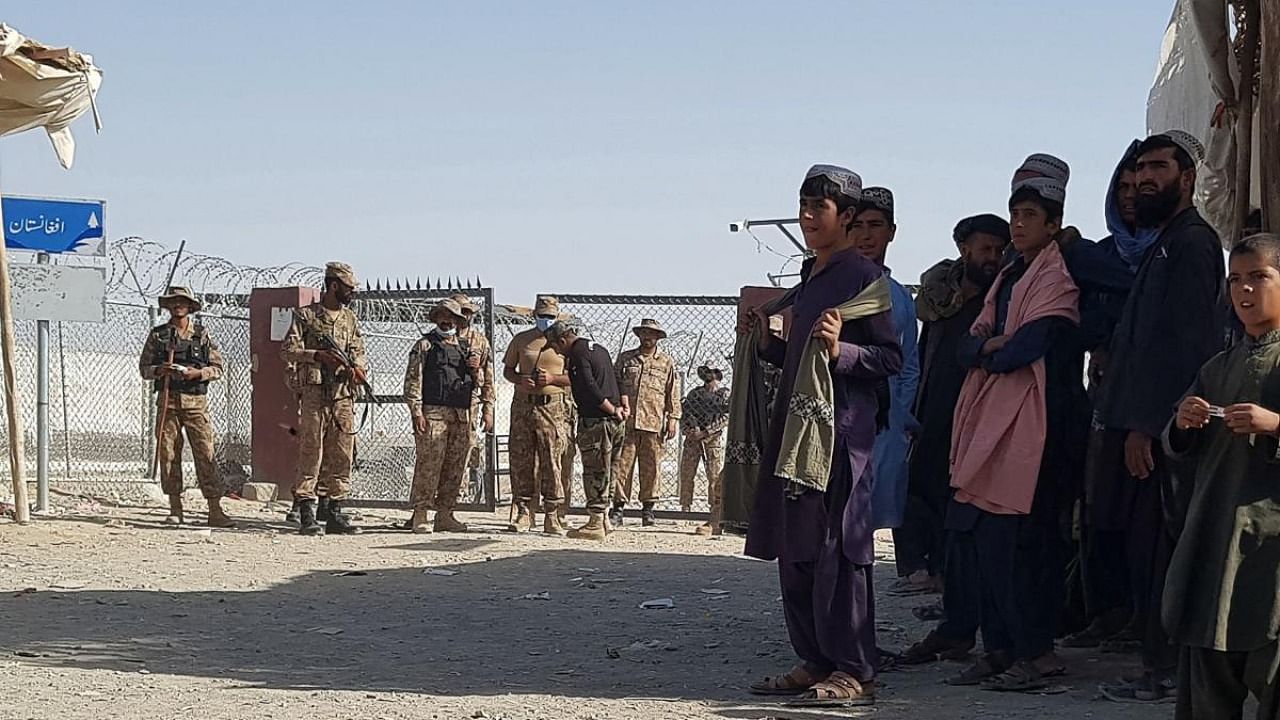 Pakistani Paramilitary soldiers stand guard as stranded people wait for the reopening of the border crossing point which was closed by the authorities, in Chaman on August 12, 2021, after the Taliban took control of the Afghan border town in a rapid offensive across the country. Credit: AFP Photo
