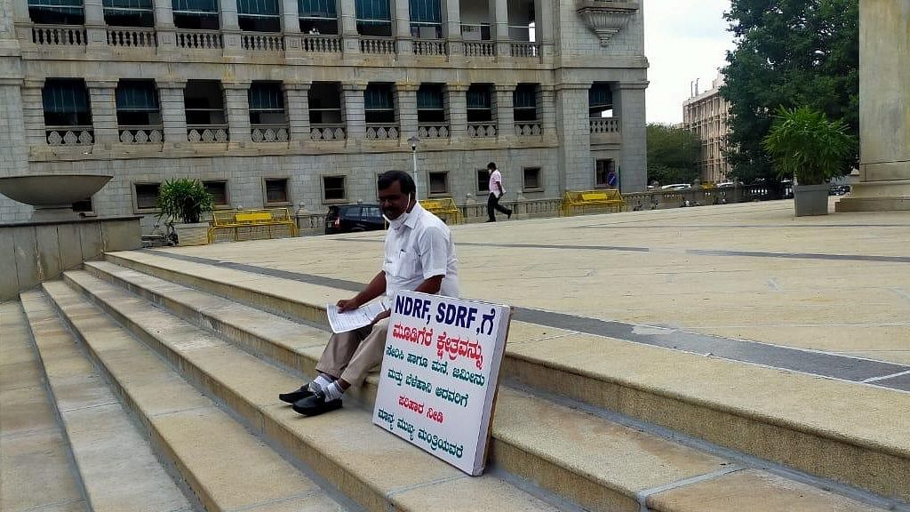 Kumaraswamy sat in protest in front of Mahatma Gandhi’s statue in Vidhana Soudha with a placard addressed to Chief Minister Basavaraj Bommai seeking NDRF/SDRF funds for Mudigere and compensation to those who lost their homes, land and crops.Credit: Special arrangement