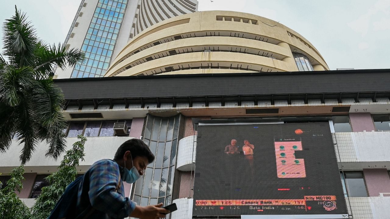 A pedestrian checks his phone as he walks past the BSE. Credit: AFP Photo