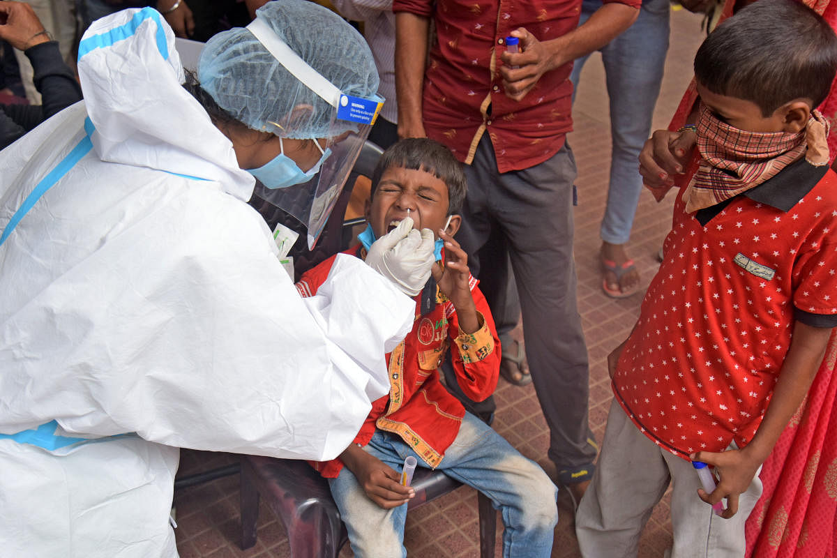 A healthcare worker collects a child's swab samples for Covid testing at the City railway station in Majestic. Credit: DH File Photo/PUSHKAR V