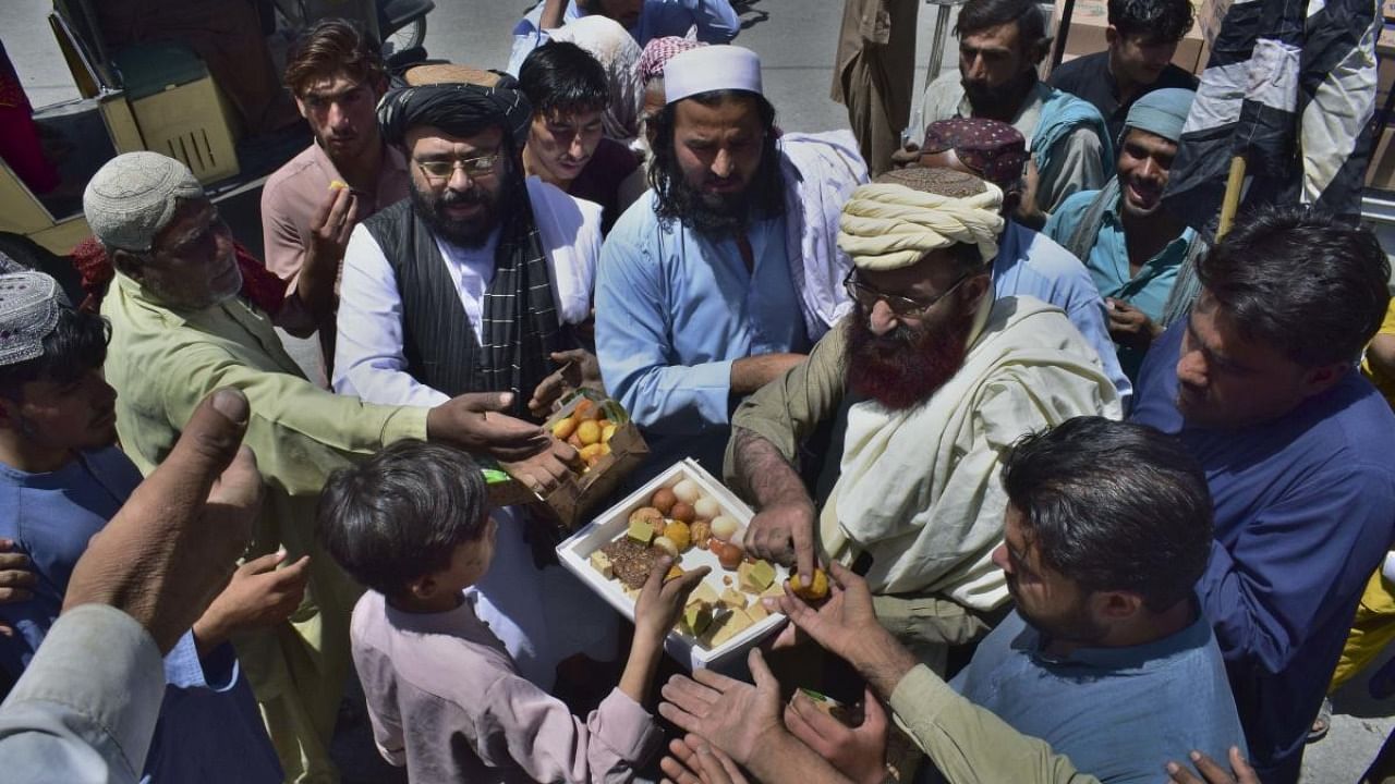 Leaders of the Pakistani religious group Jamiat Ulema-e Islam Nazryate party distribute sweets among people on a market area to celebrate the Talibans capturing the largest cities of Afghanistan, on a market area in Quetta, Pakistan. Credit: AP Photo