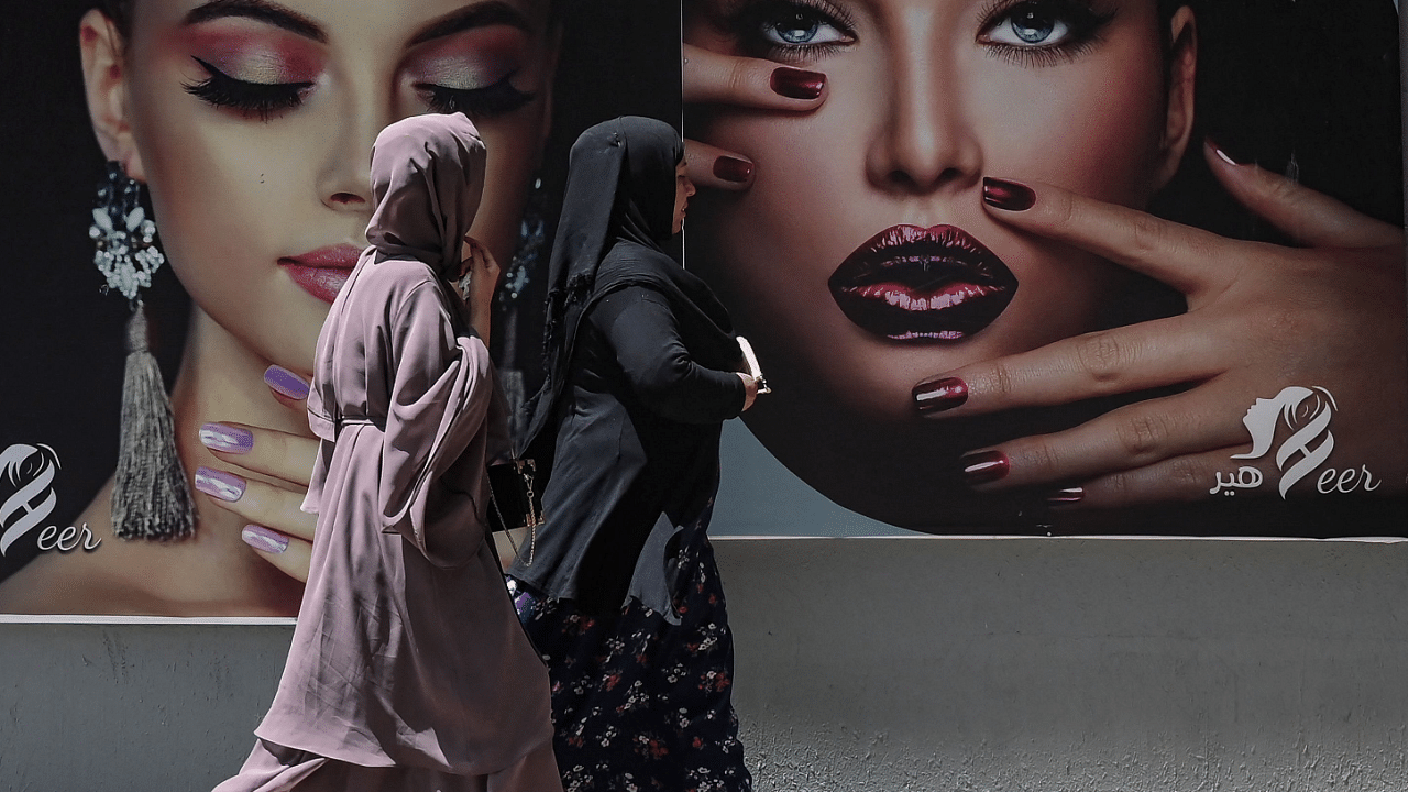 Burqa clad women walks past a billboard put up on the wall of a beauty salon in Kabul. Credit: AFP Photo