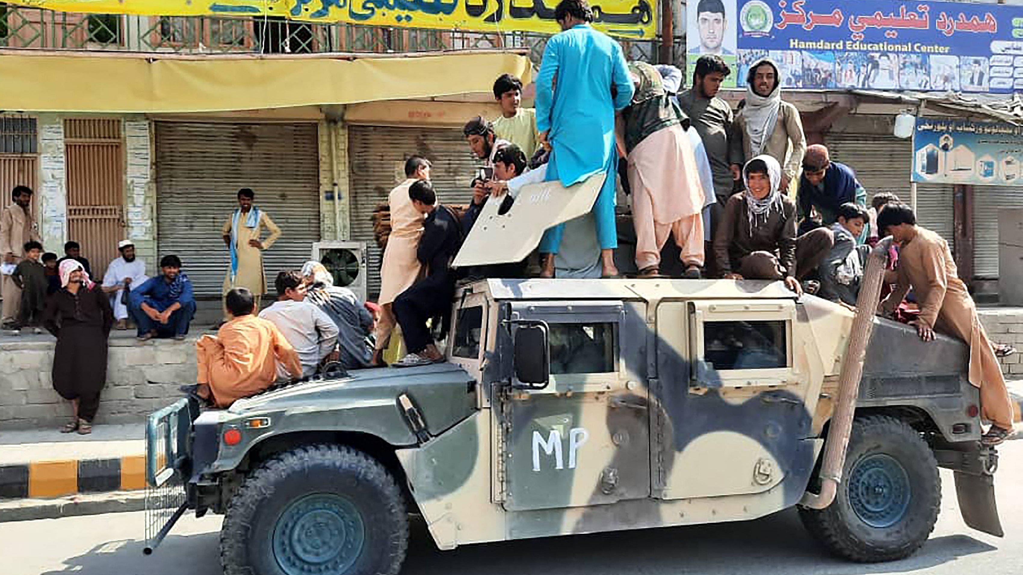 Taliban fighters and local residents sit over an Afghan National Army (ANA) humvee vehicle along the roadside in Laghman province. Credit: AFP Photo