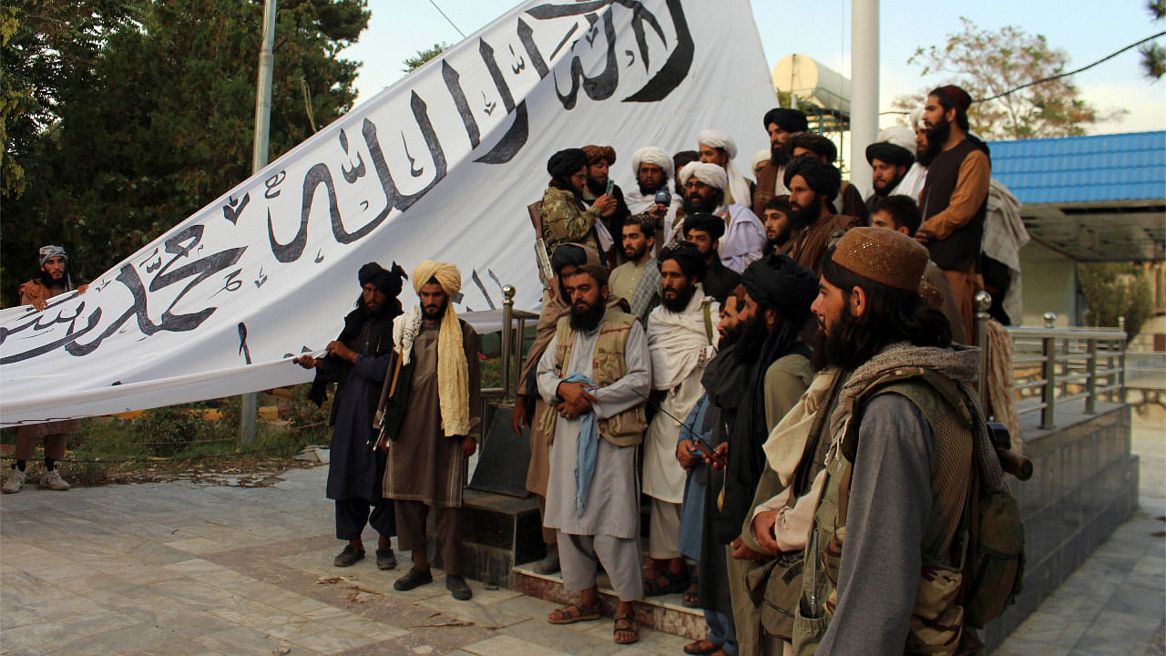 Taliban fighters poses for a photograph while raising their flag Taliban fighters raise their flag at the Ghazni provincial governor's house, in Ghazni. Credit: AP Photo