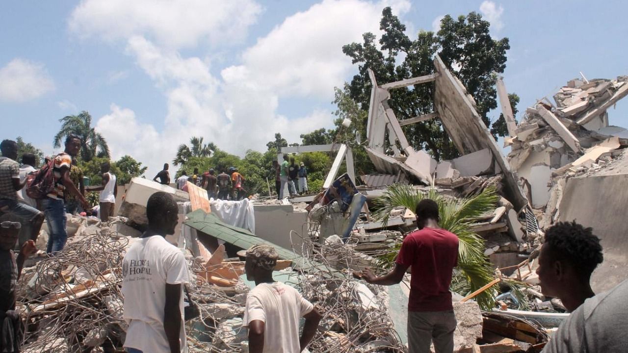 People search through the rubble of what used to be the Manguier Hotel after the earthquake hit on August 14, 2021 in Les Cayes, southwest Haiti. Credit: AFP Photo