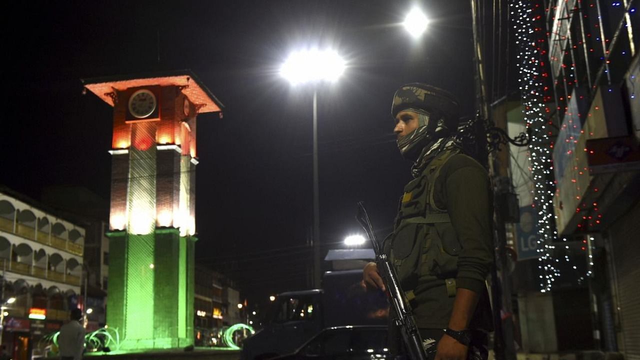 Security personnel stands guard at Lal Chowk illuminated in tricolour on the eve of 75th Independence Day celebrations, in Srinagar. Credit: PTI Photo