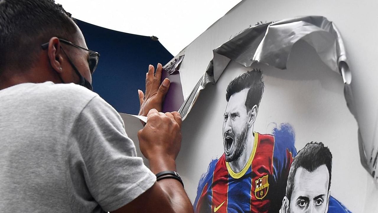 A worker removes posters featuring Barcelona's departing Argentinian forward Lionel Messi at the Camp Nou stadium in Barcelona. Credit: AFP Photo