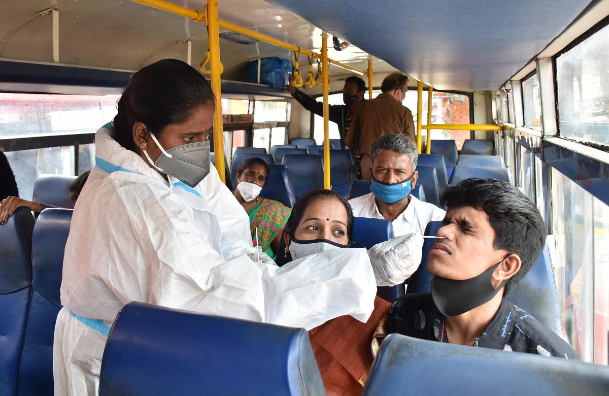 A health worker collects samples of a passenger in KSRTC bus for Covid test, in Bengaluru on Saturday. Credit: DH Photo/B K Janardhan