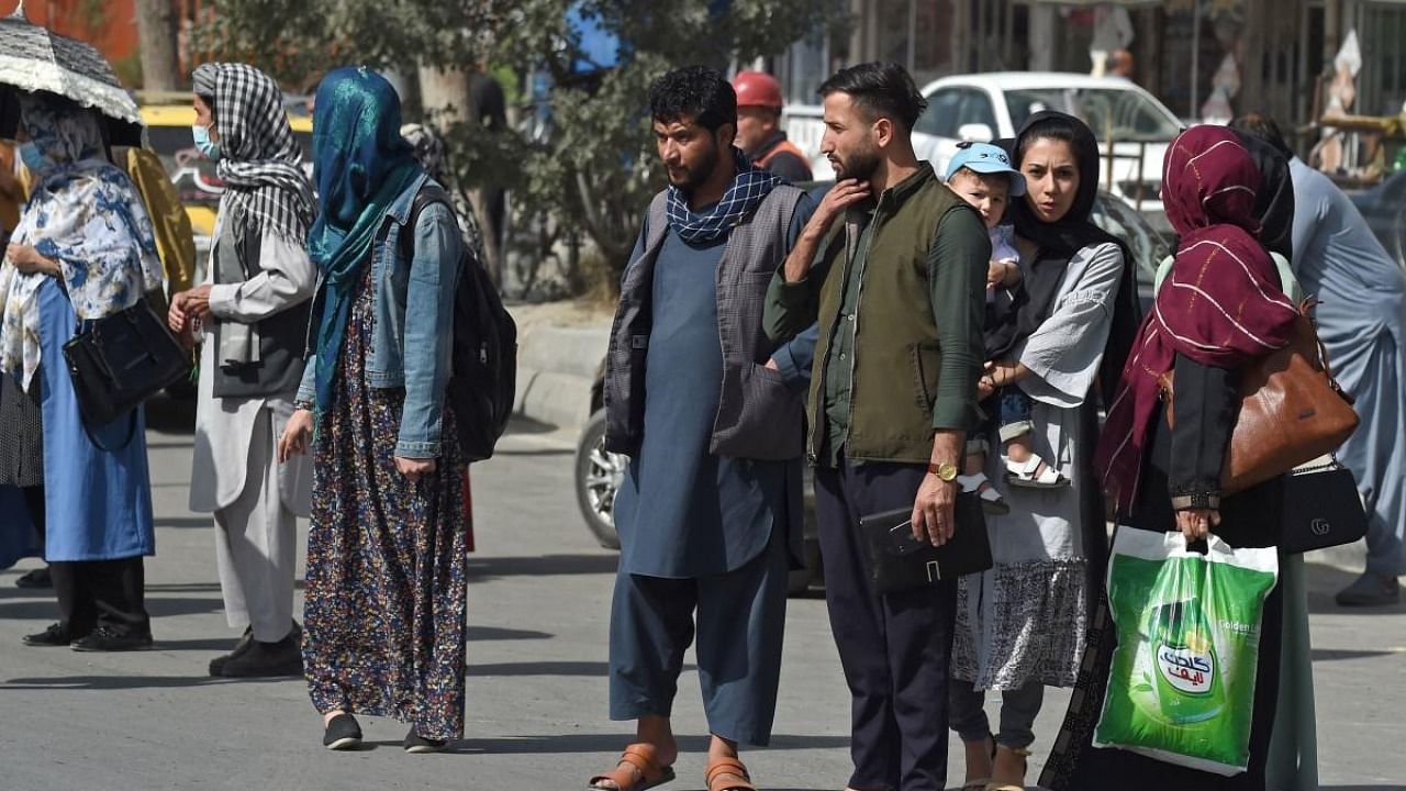 Afghan people stand along the roadside as they wait for taxi in Kabul on August 15, 2021. Credit: AFP Photo