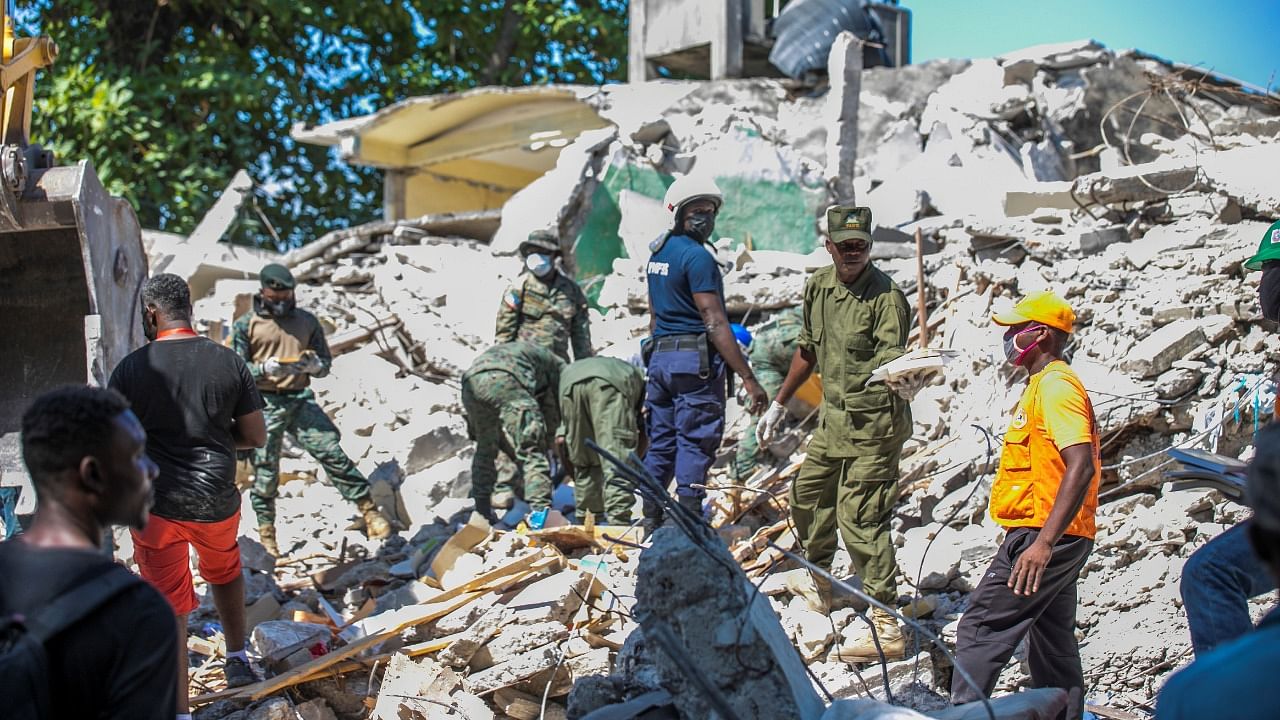 Soldiers and members of a rescue and protection team clean debris from a house after a 7.2 magnitude earthquake in Les Cayes, Haiti. Credit: AFP Photo