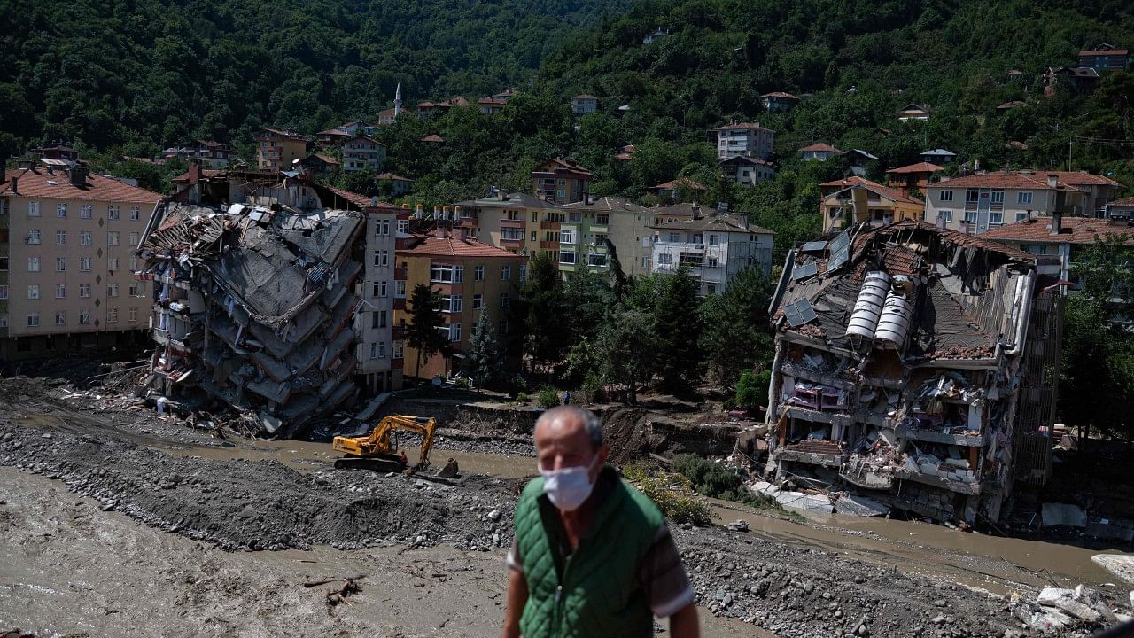 A digger works near two collapsed buildings following flash floods the day before in the town of Bozkurt. Credit: AFP Photo