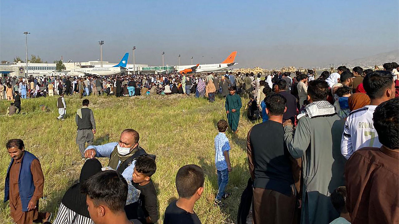 Afghans (L) crowd at the airport as US soldiers stand guard in Kabul. Credit: AFP Photo