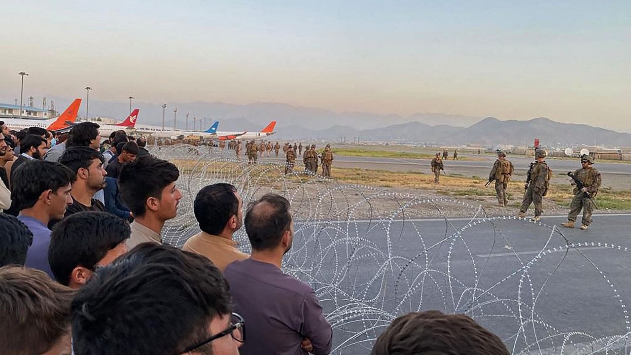 Afghans (L) crowd at the airport as US soldiers stand guard in Kabul. Credit: AFP Photo