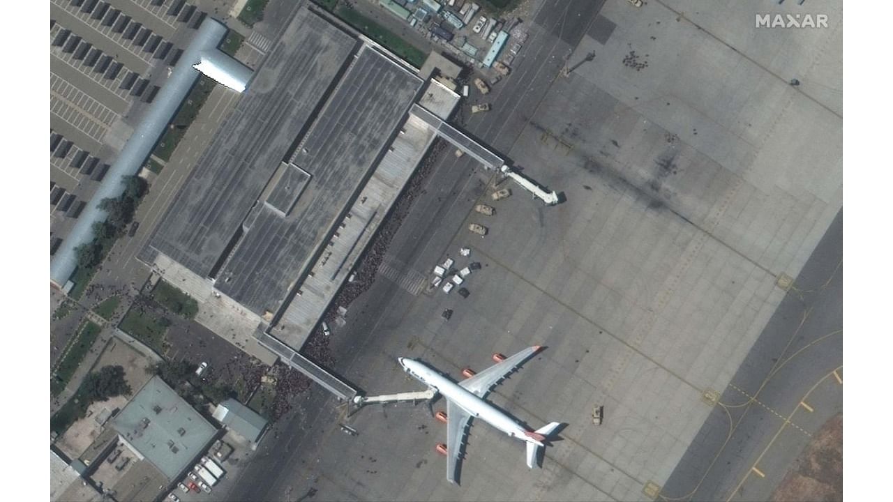 This handout satellite image released by Maxar Technologies shows crowds of people at the terminal, during the chaotic scene underway at Kabul’s Hamid Karzai International Airport in Afghanistan as thousands of people converged on the tarmac and airport runways as countries attempt to evacuate personnel from the city. Credit: AFP Photo/Satellite image ©2021 Maxar Technologies