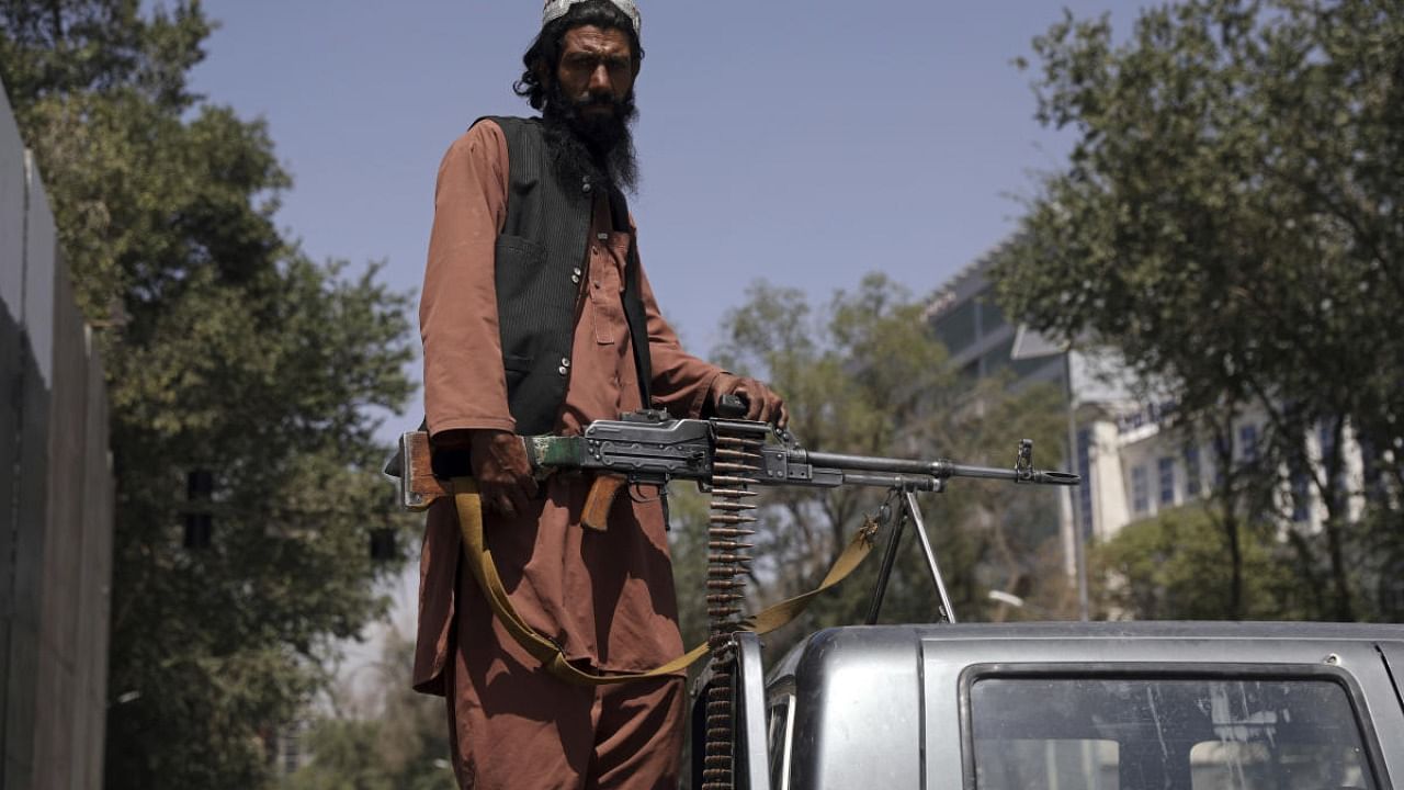 A Taliban fighter sits on the back of vehicle with a machine gun in front of the main gate leading to the Afghan presidential palace, in Kabul, Afghanistan. Credit: AP Photo