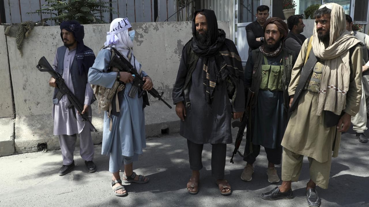 Taliban fighters stand guard at the main gate leading to the Afghan presidential palace, in Kabul, Afghanistan. Credit: AP Photo