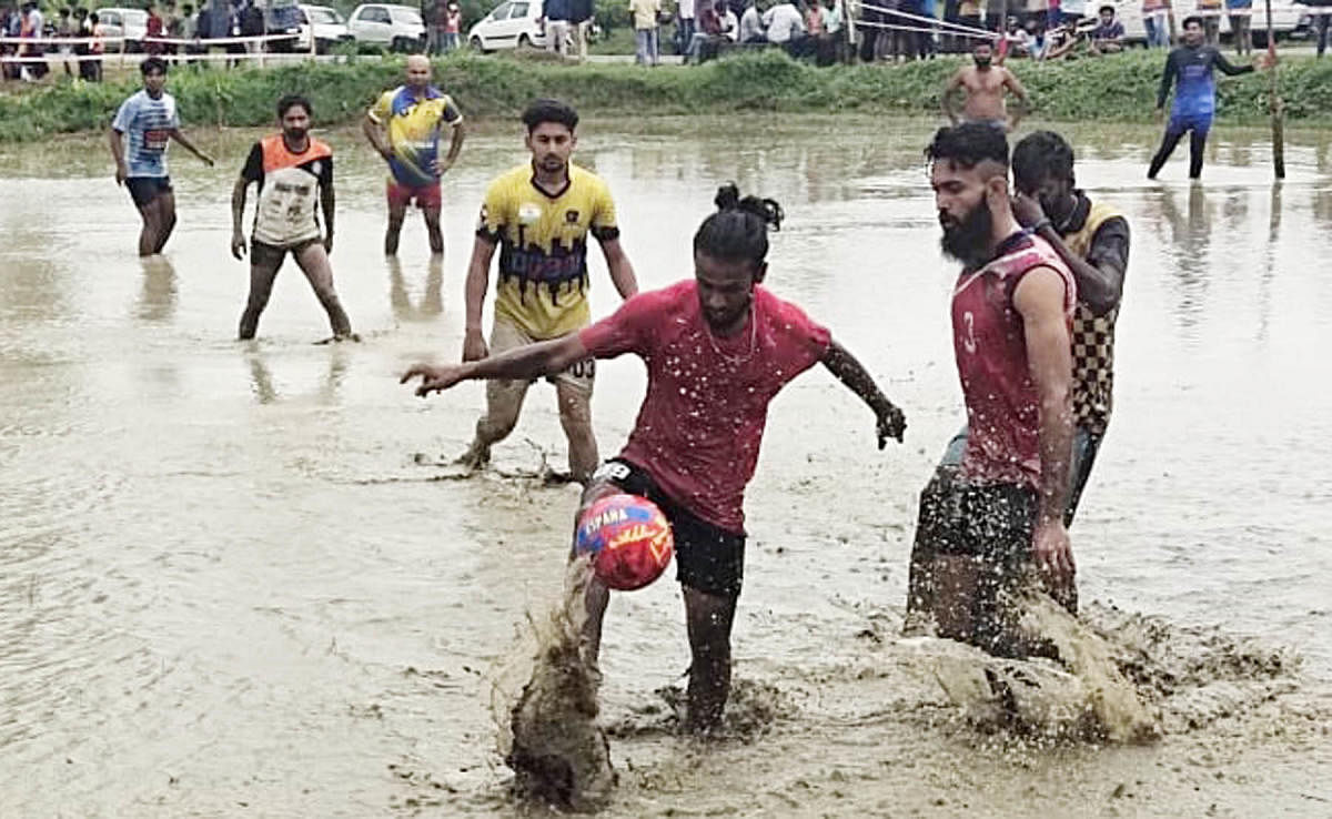 Youth take part in a marshy field football match.