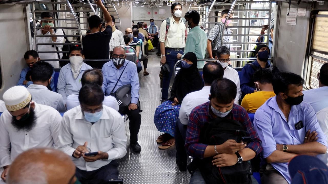 Commuters wearing protective face masks ride in a suburban train after authorities resumed the train services for vaccinated passengers amid the coronavirus pandemic in Mumbai. Credit: Reuters photo