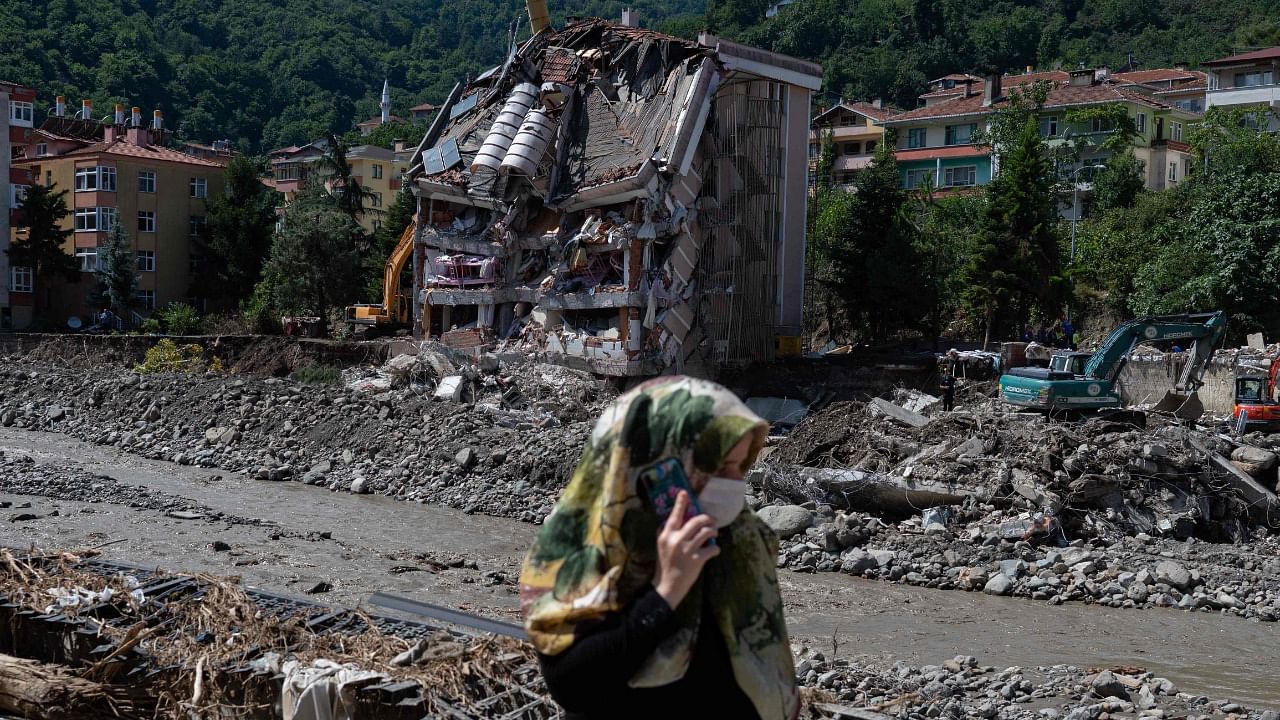 A woman walks past the front of a building is collapsed after flash floods destroyed parts of Bozkurt town in the district of Kastamonu, in the Black Sea region of Turkey. Credit: AFP Photo