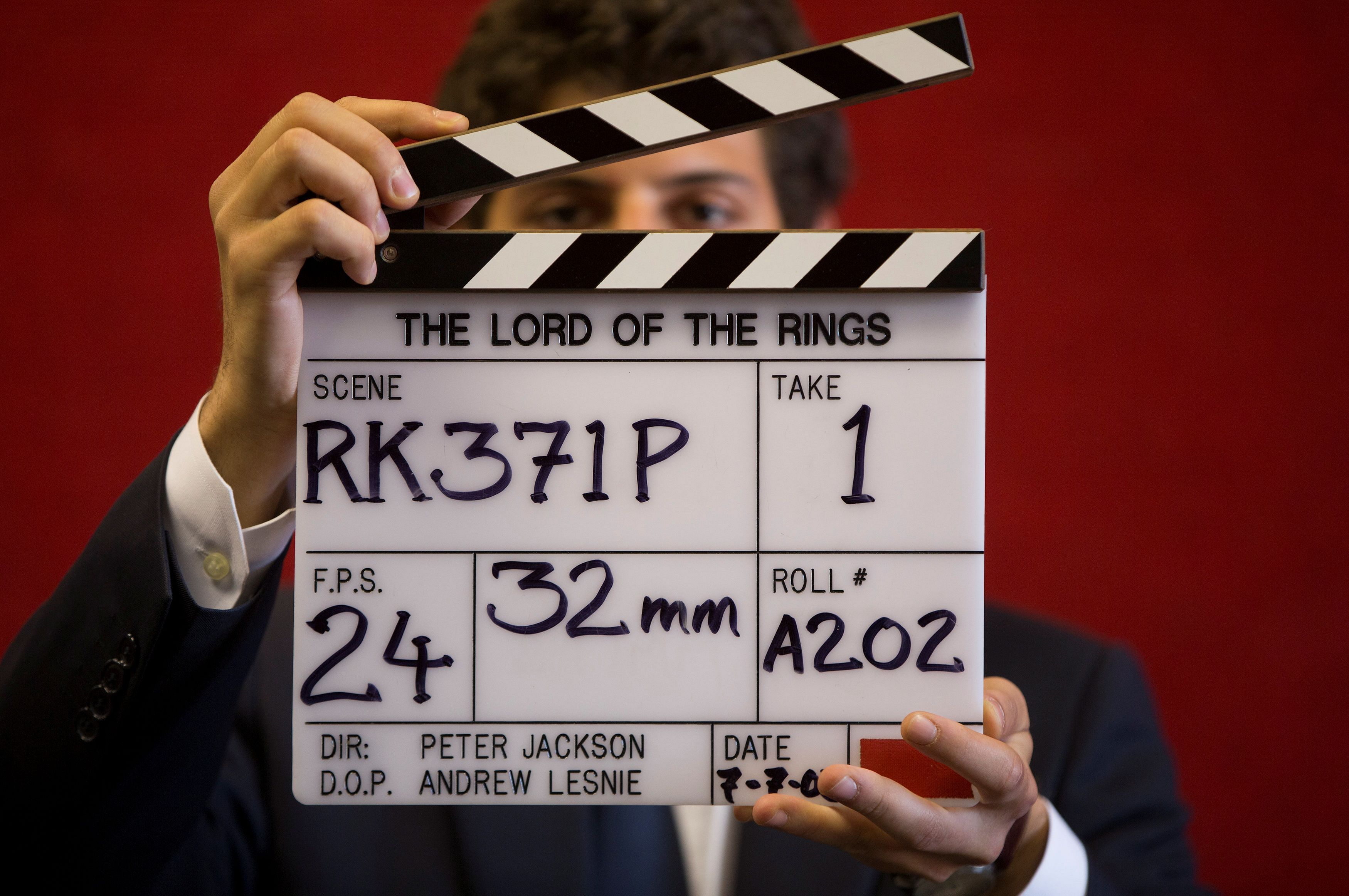 A gallery assistant poses for a photograph with a clapper board used in the filming of the Lord of the Rings. Credit: Reuters File Photo