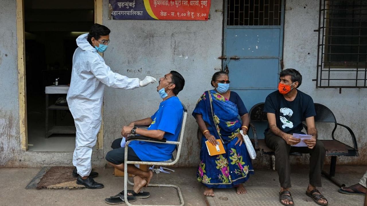 A health worker takes a swab sample of a resident for a Covid-19 coronavirus test at a medical centre in Dharavi slums in Mumbai. Credit: AFP Photo