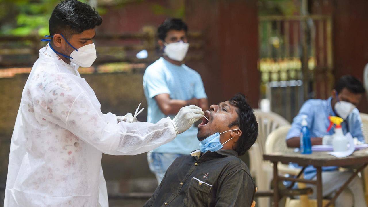 A health worker takes a swab of residents to check Covid 19, in Mumbai. Credit: PTI Photo