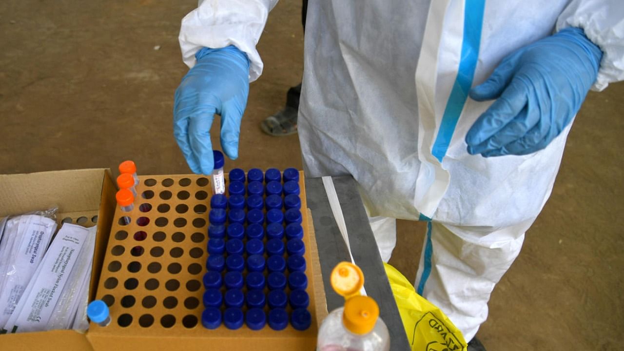 A health worker in PPE kit collects swab to test for Covid-19 in Bengaluru. Credit: DH Photo