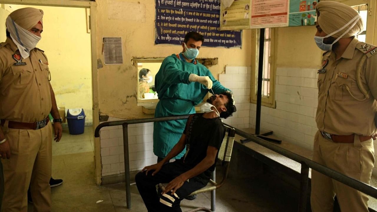 A health worker collects a nasal swab sample from a man to test for the Covid-19. Credit: AFP Photo