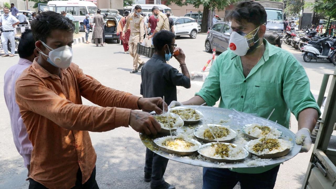Volunteers serve food to the needy people during Covid-induced curfew in Jammu. Credit: PTI Photo