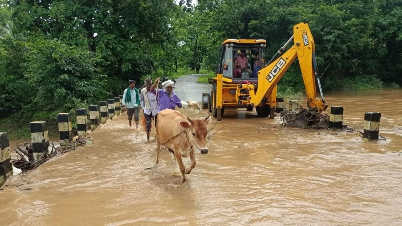 Villagers cross a flooded bridge at Kumbarakoppa village in Alnavar taluk in Dharwad district on Thursday. Credit: DH Photo